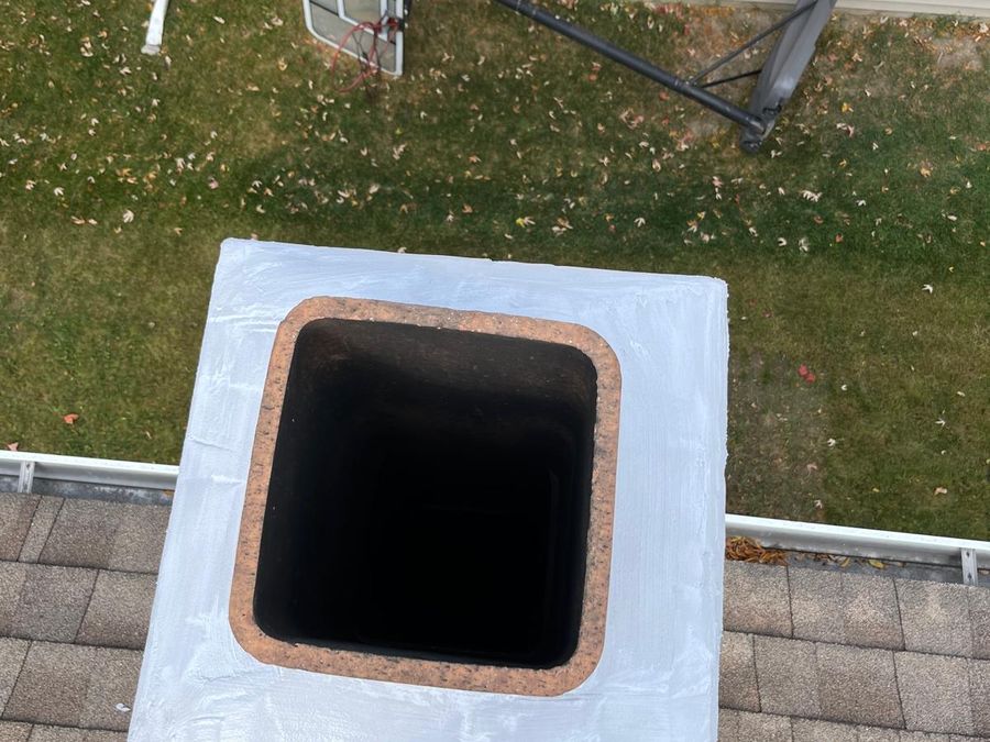 Chimney crown coated with white sealant, seen from above