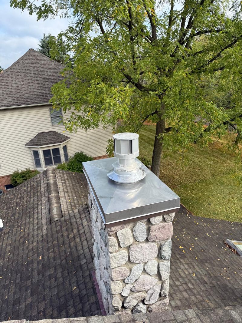 The same fieldstone chimney with a new stainless steel cover and cap