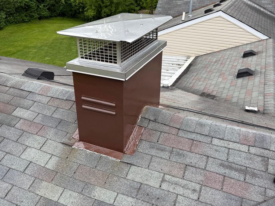 Chimney chase painted brown with a new stainless chase cover and cap on a shingle roof