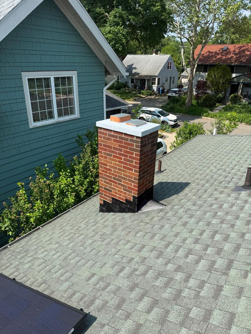The same brick chimney with a coated crown, flue covers and new black flashing